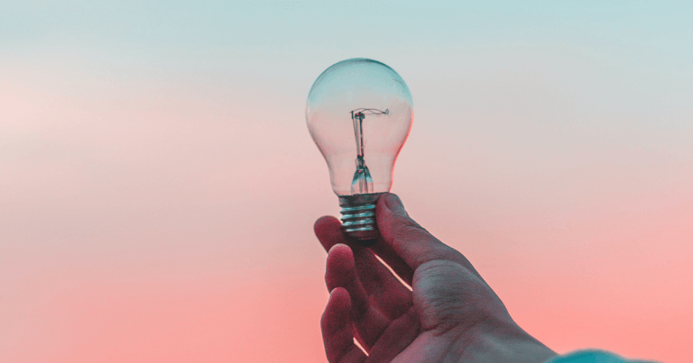 A hand holding up a light bulb